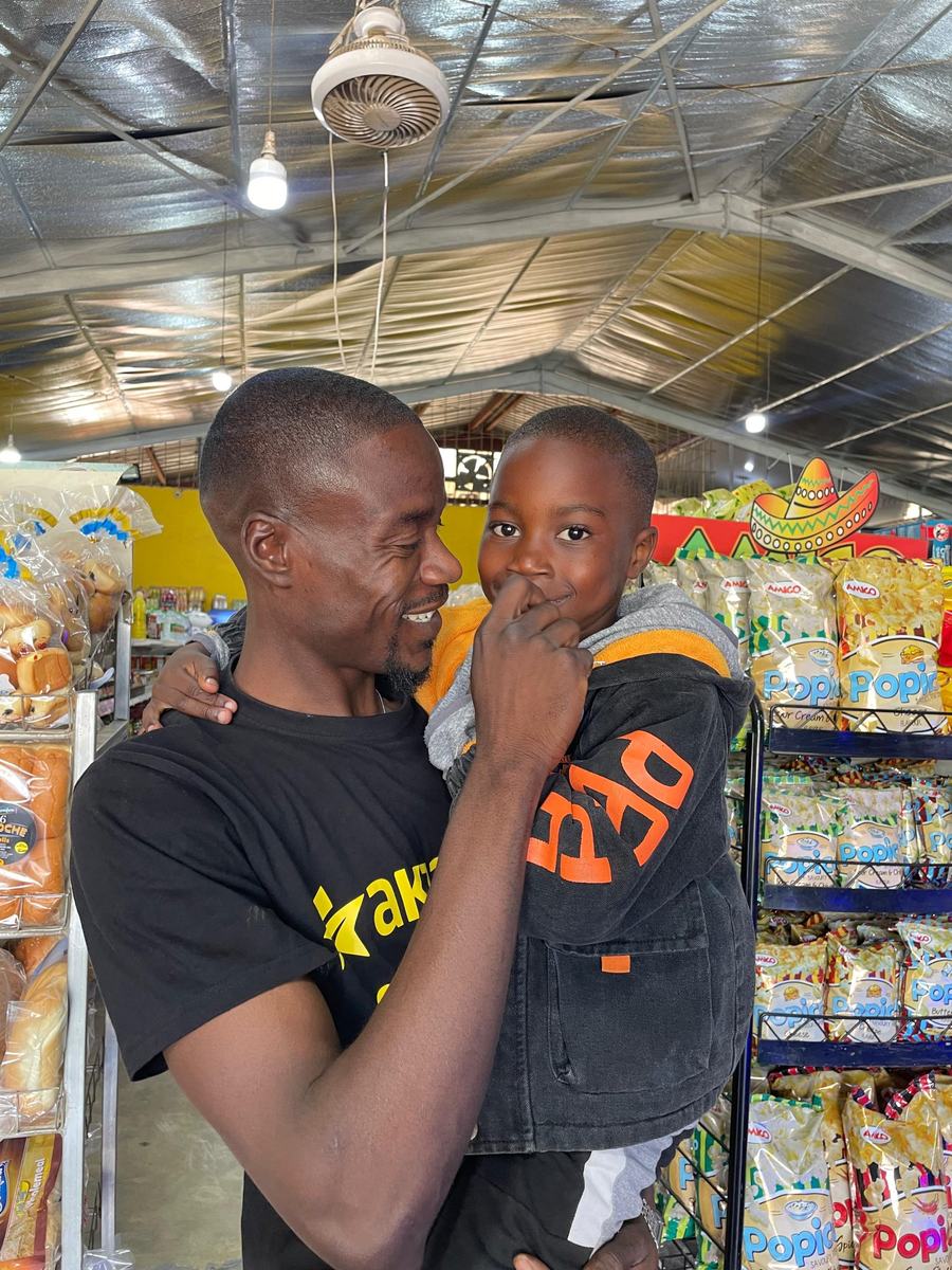 Simon Mwaba, AKZAM Vice President, holding a young boy and smiling