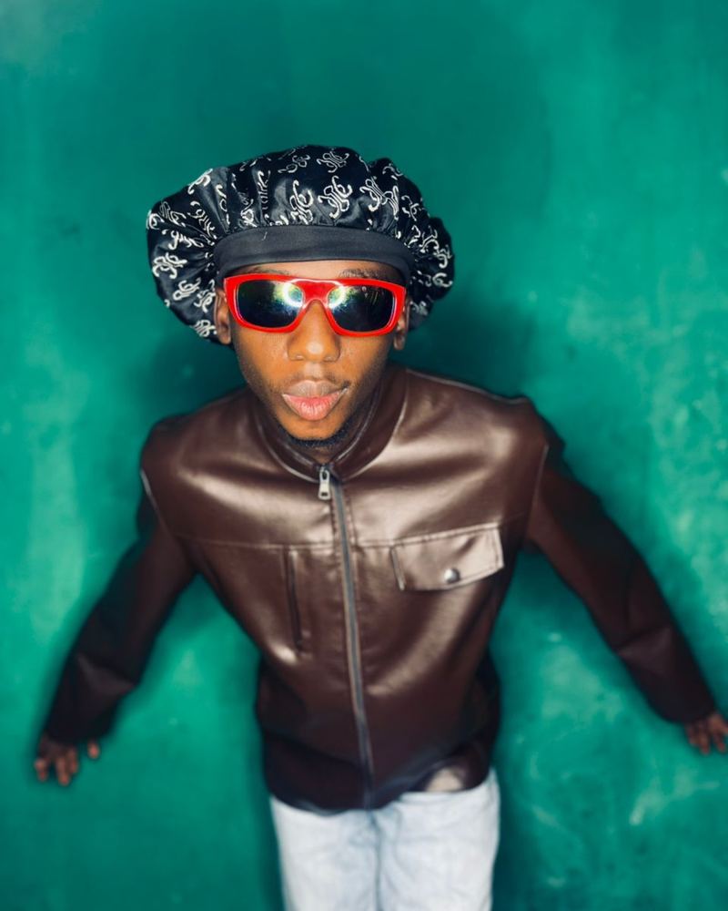 SOCO, comedy and lifestyle creator, in red sunglasses against a green wall